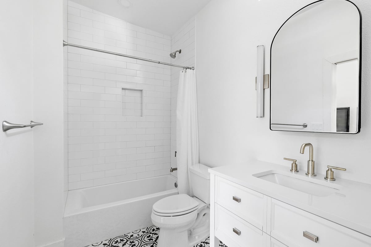 ADU bathroom with tub and vanity by RedOven Builds in 3102 S Oak Dr TX featuring white tile and modern fixtures