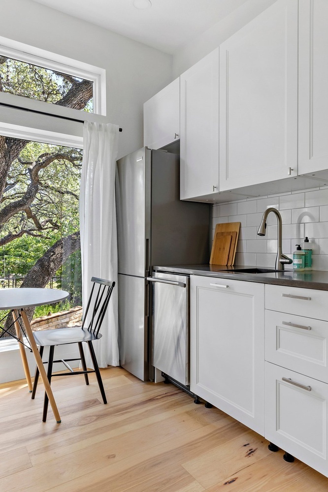 bright ADU kitchen by RedOven Builds in 3102 S Oak Dr TX with white cabinets, stainless appliances, and large window views