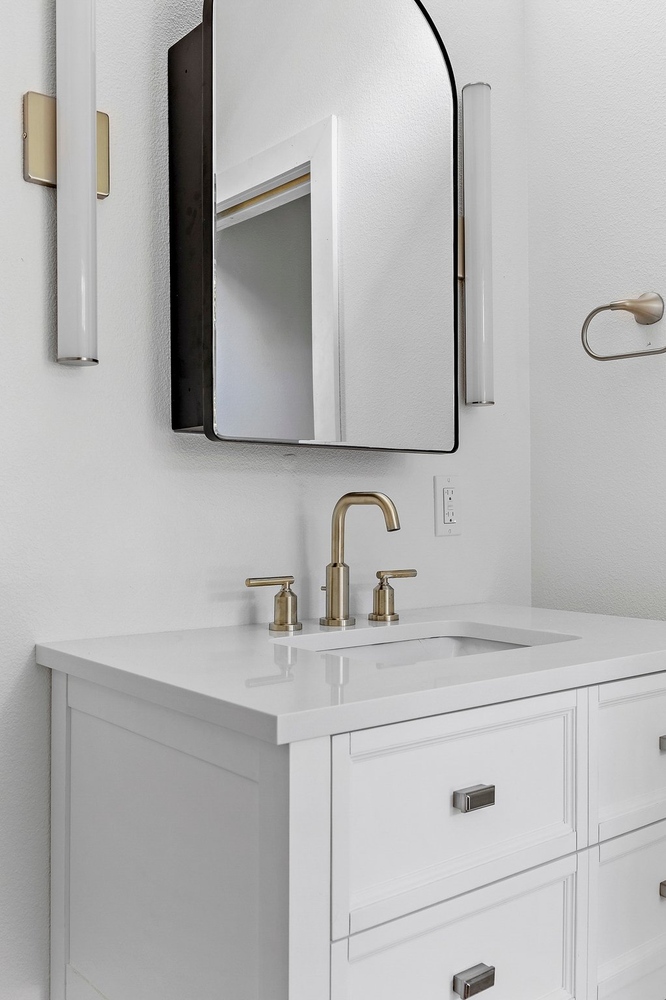 close-up of ADU bathroom vanity by RedOven Builds in 3102 S Oak Dr TX with brass faucet and sleek white countertop