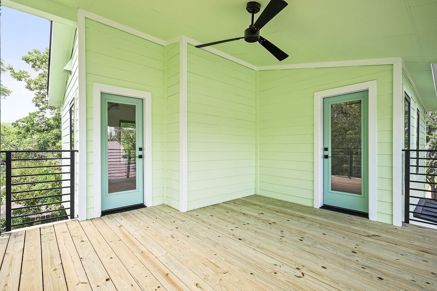 Balcony with two glass doors, ceiling fan, and wood deck in Brentwood, TX ADU by RedOven Builds