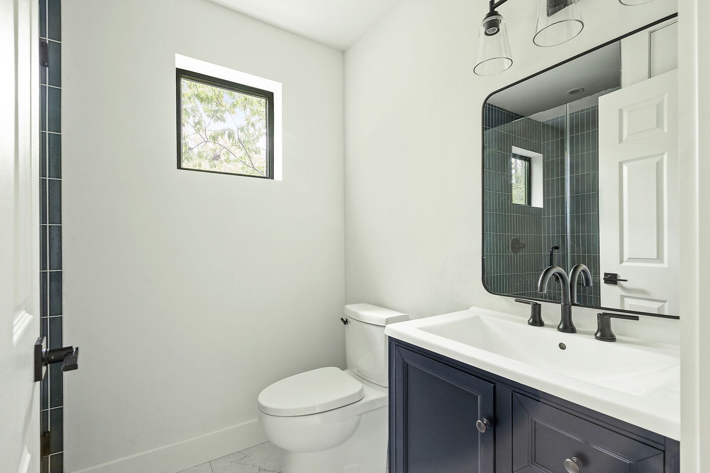 Bathroom with blue vanity, mirror, and shower in Brentwood, TX ADU by RedOven Builds