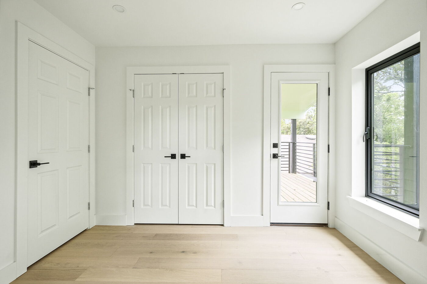 Bedroom with double closet doors, window, and balcony access in Brentwood, TX ADU by RedOven Builds