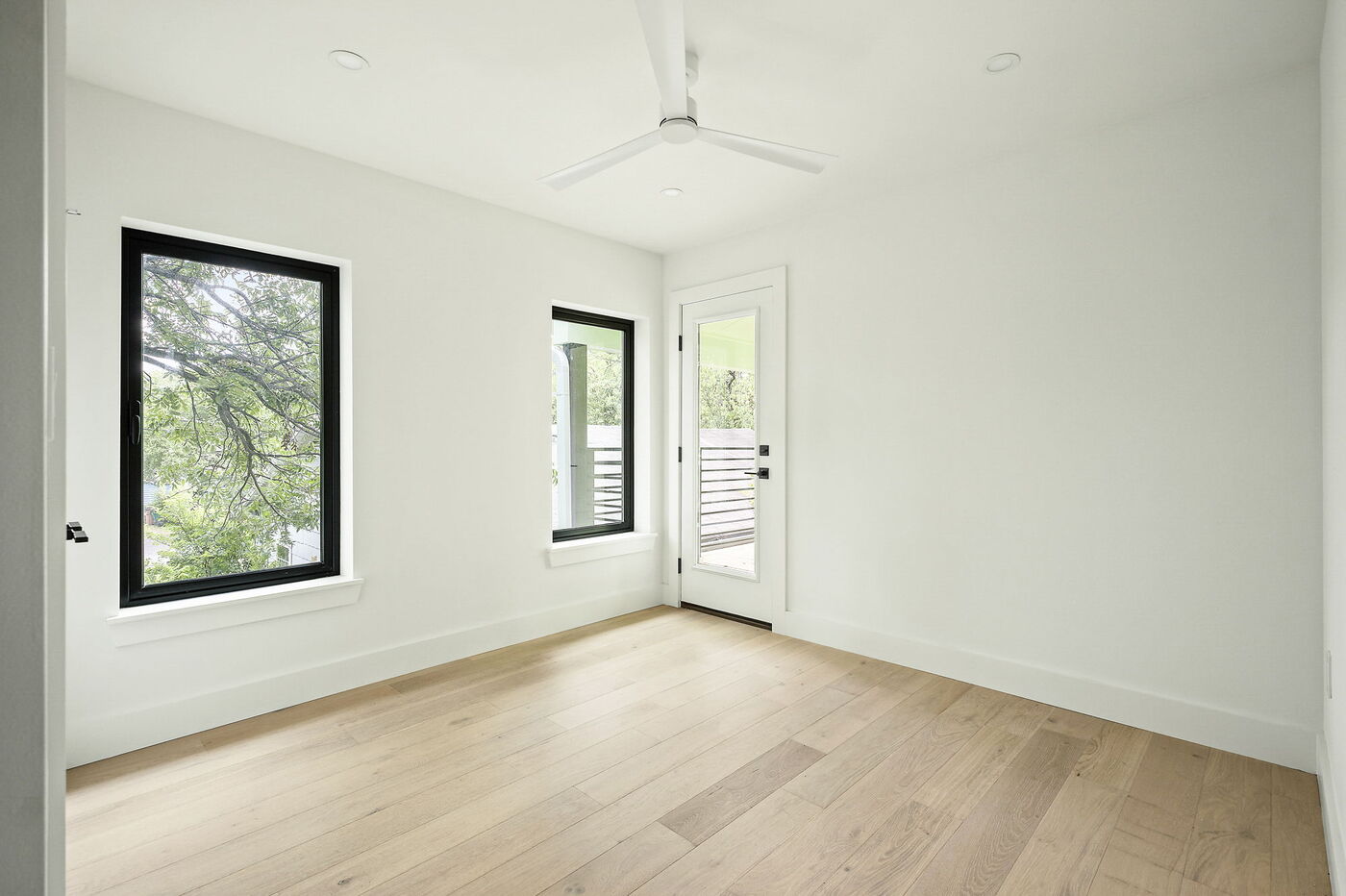 Bright bedroom with large windows, ceiling fan, and balcony door in Brentwood, TX ADU by RedOven Builds