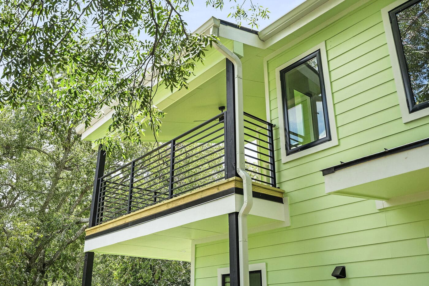 Close-up of second-story balcony with black railing on green ADU in Brentwood, TX by RedOven Builds