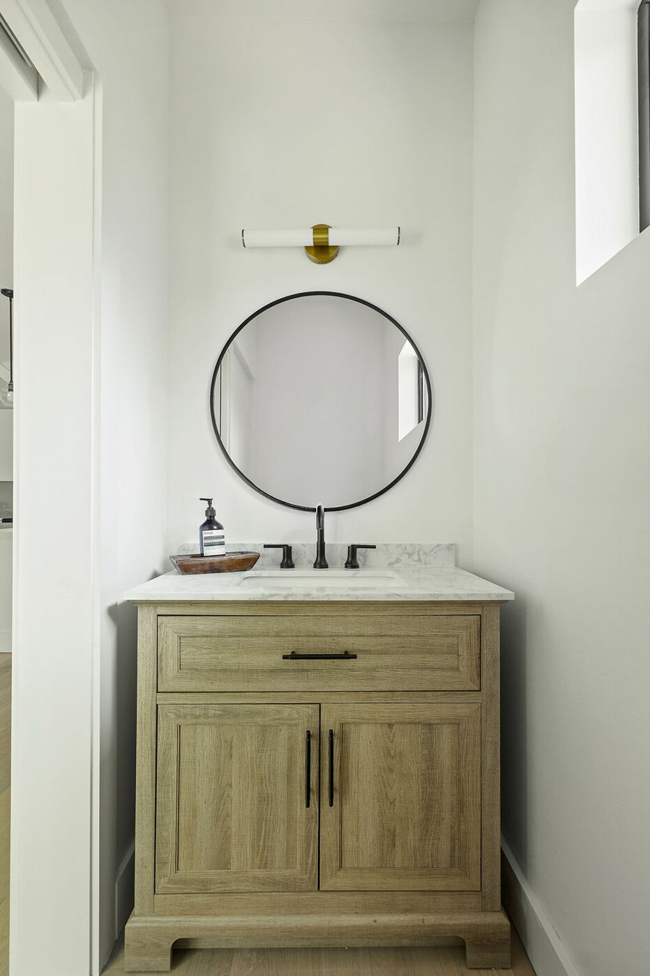 Compact bathroom with wood vanity, marble top, and black fixtures in Brentwood, TX ADU by RedOven Builds