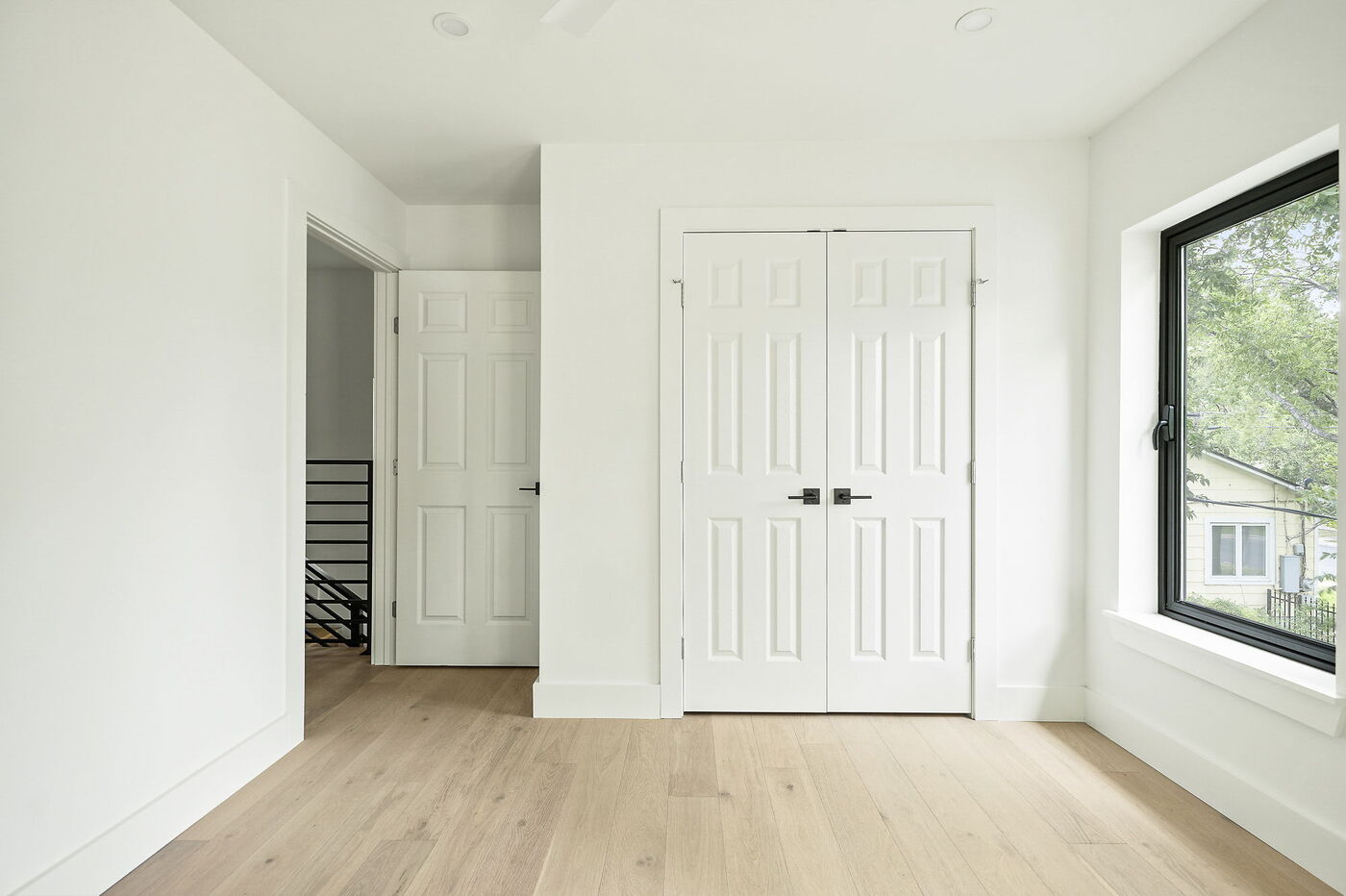 Minimal bedroom with double closet doors and natural light in Brentwood, TX ADU by RedOven Builds