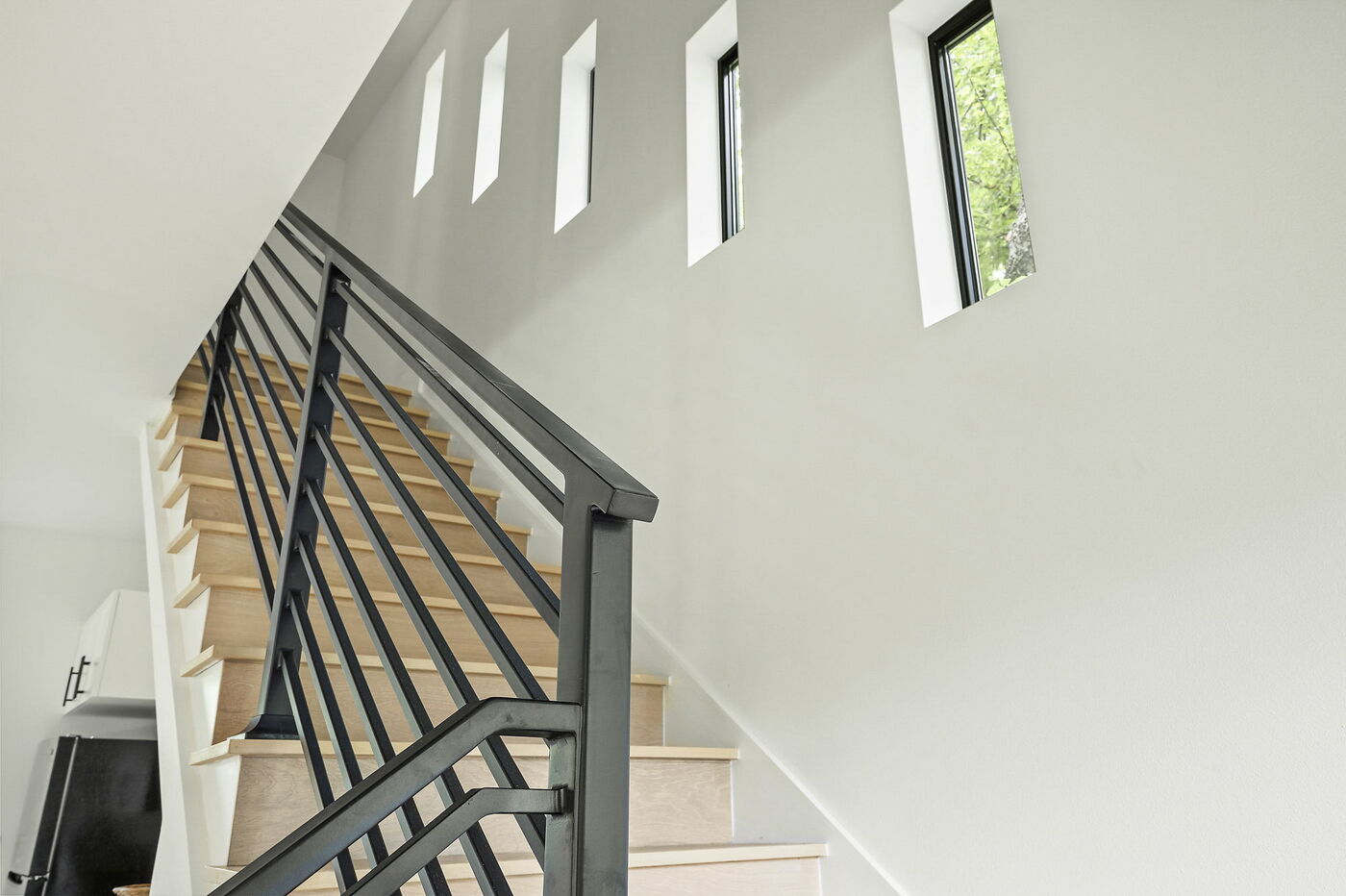 Modern staircase with wood treads and black metal railing in Brentwood, TX ADU by RedOven Builds