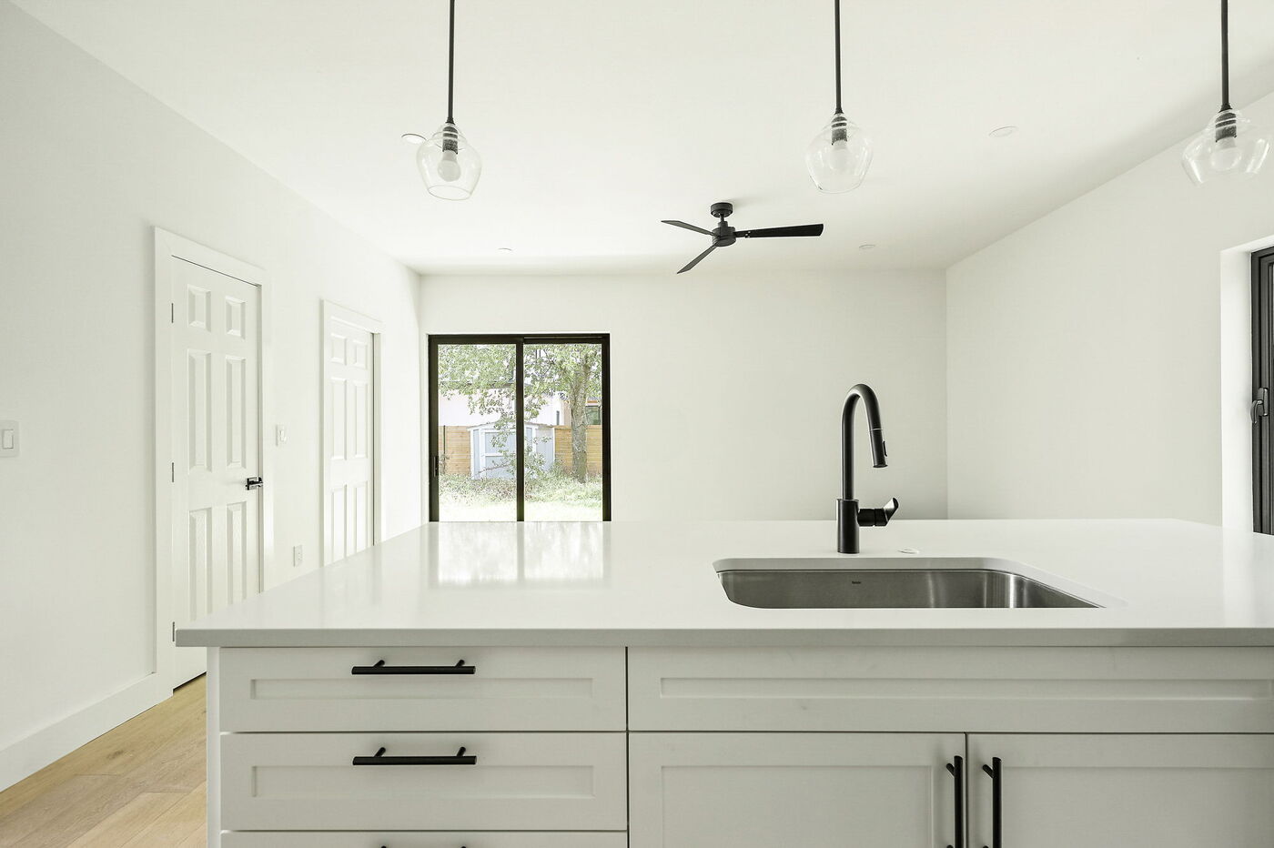 Open kitchen with large island, sink, and backyard view in Brentwood, TX ADU by RedOven Builds