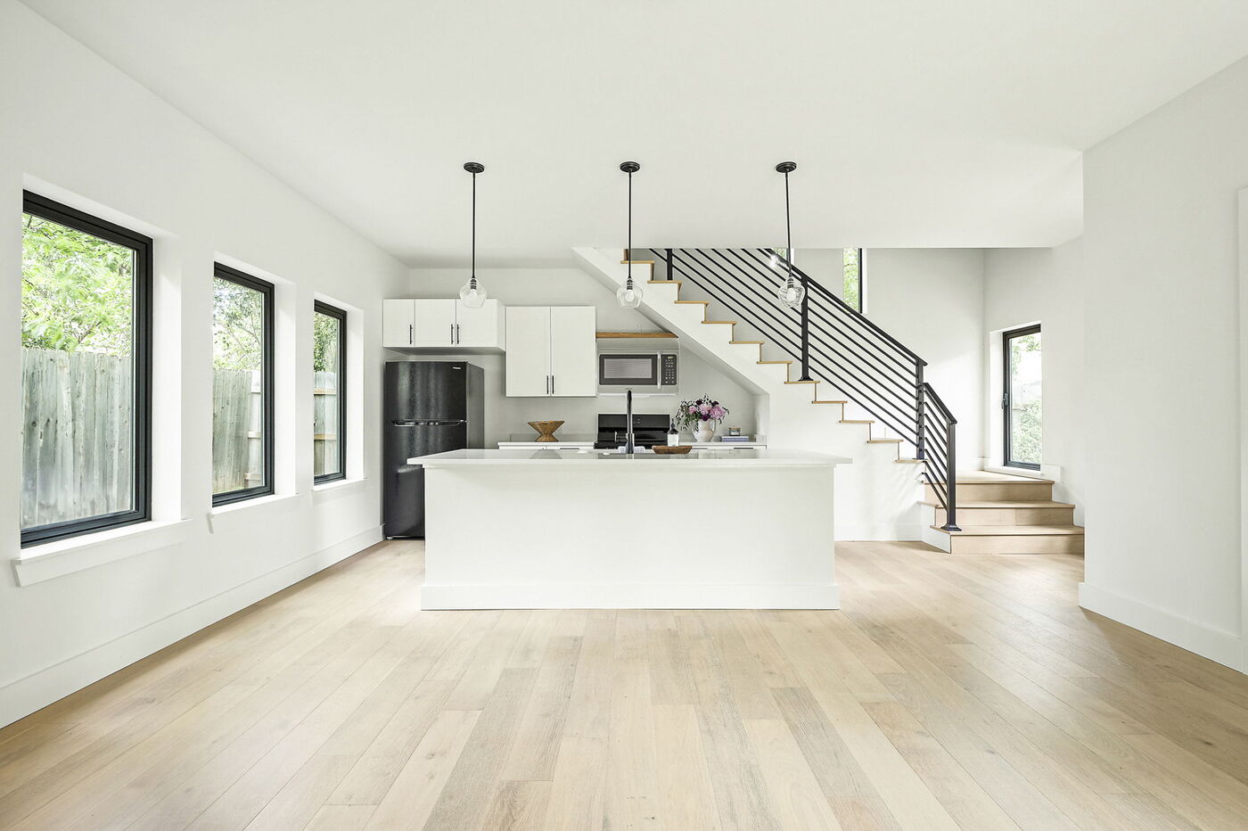 Open-concept kitchen with white island, pendant lights, and staircase in Brentwood, TX ADU by RedOven Builds