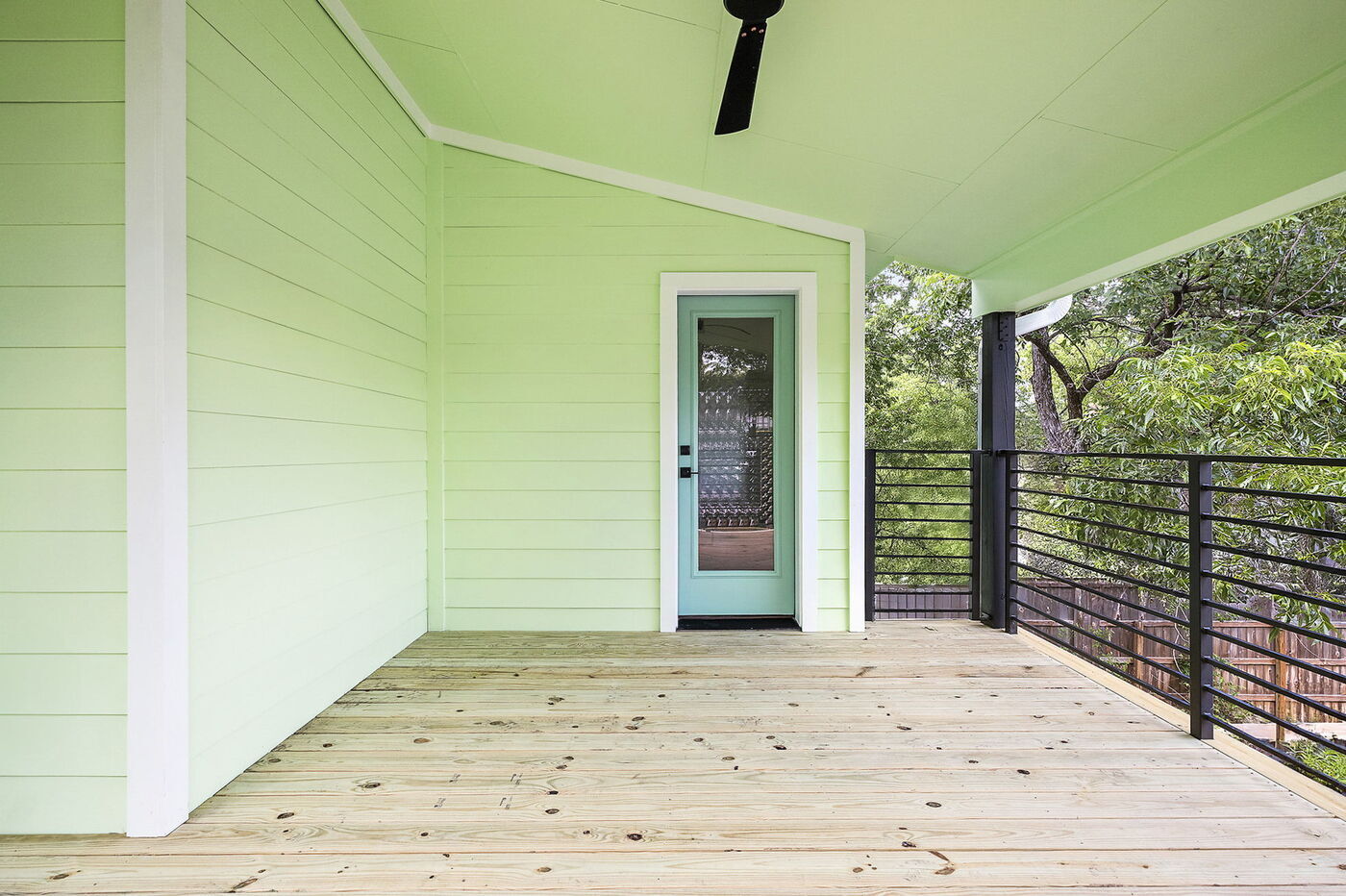 Spacious covered balcony with green siding and railing in Brentwood, TX ADU by RedOven Builds