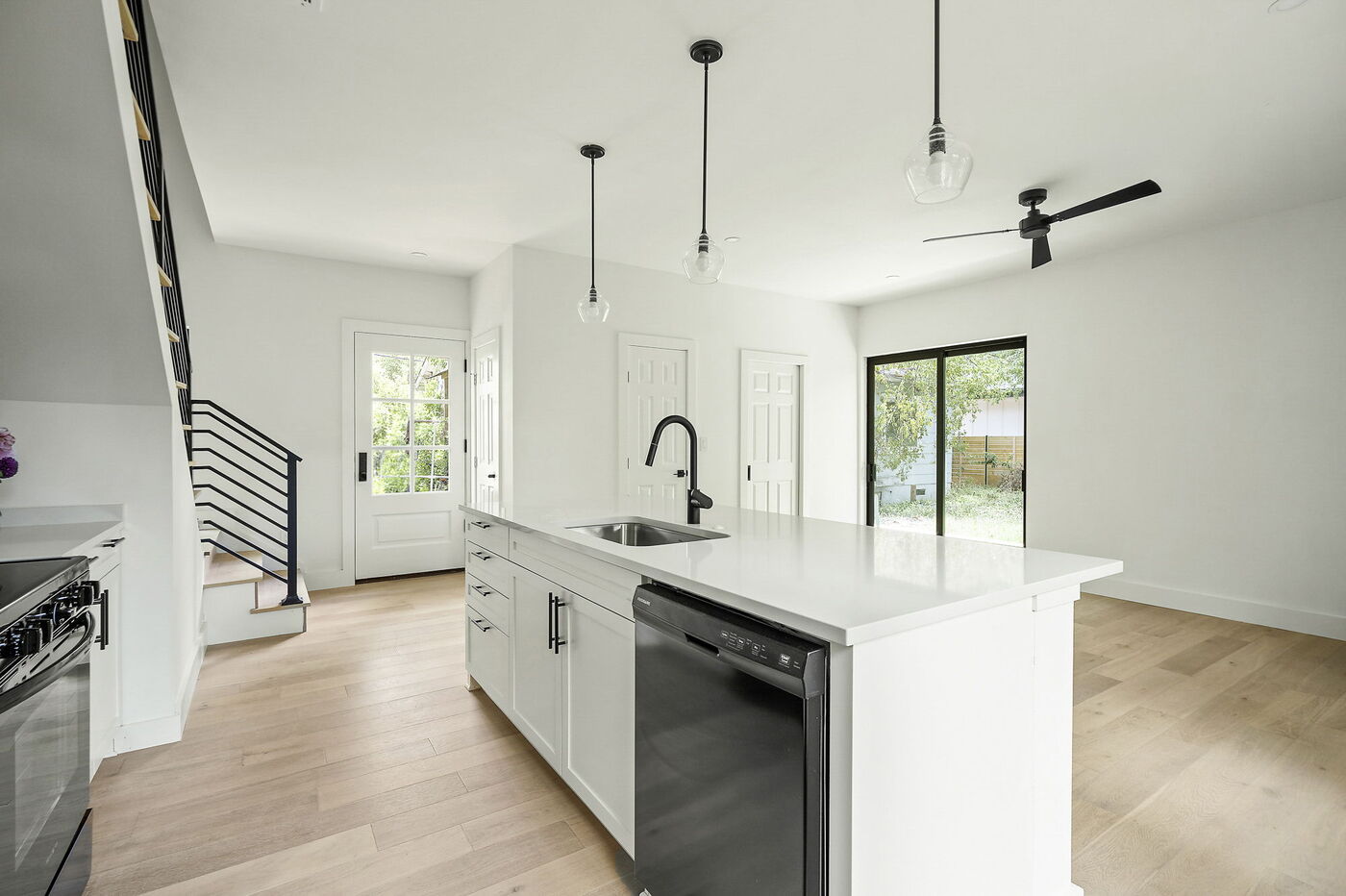 Spacious kitchen with white island, black appliances, and sliding glass doors in Brentwood, TX ADU by RedOven Builds