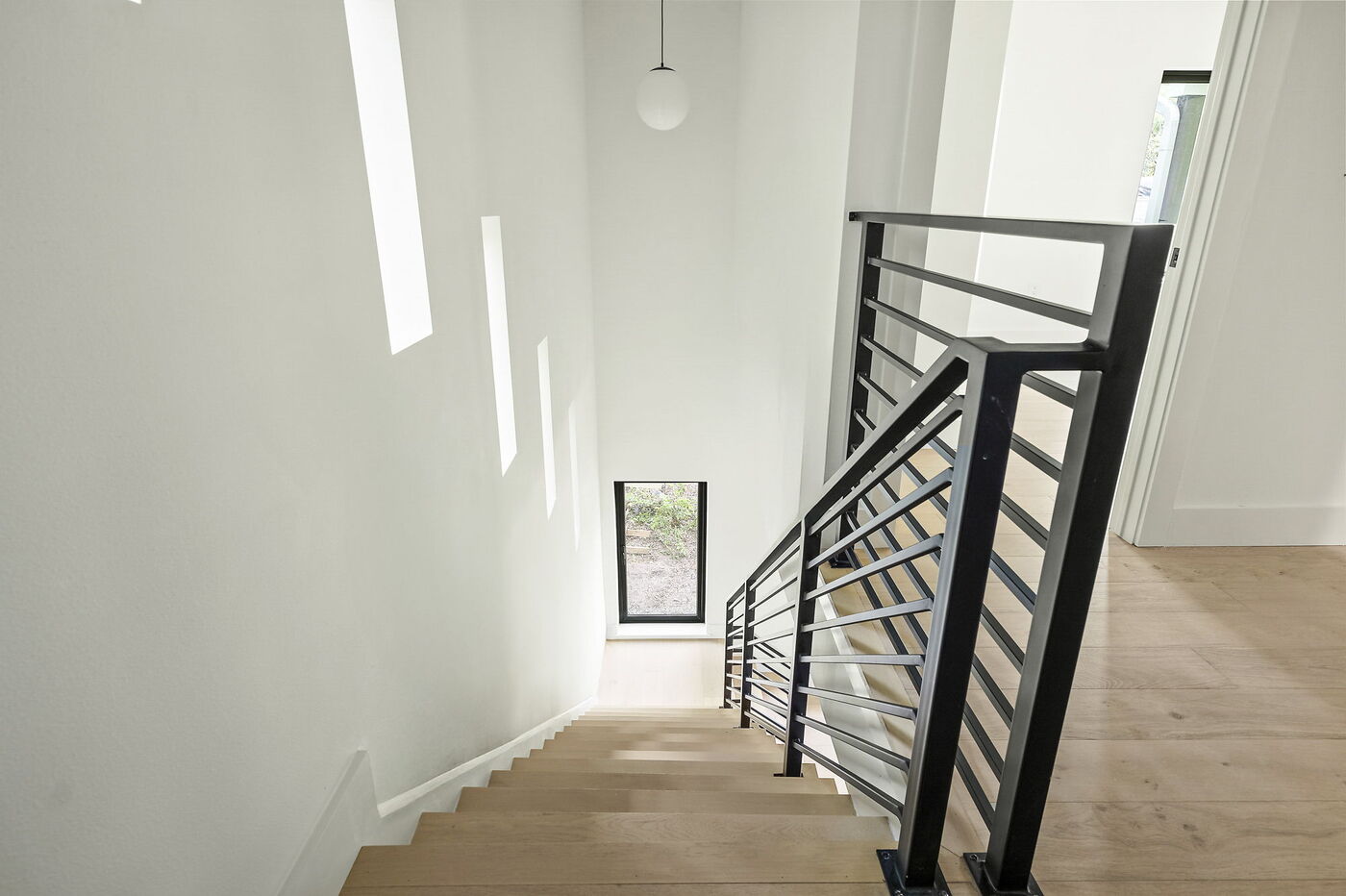 Staircase view from above with natural light and black railing in Brentwood, TX ADU by RedOven Builds
