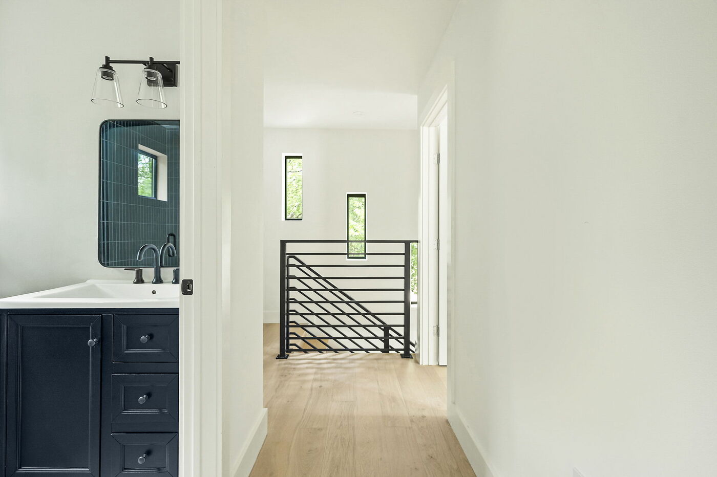 Upstairs hallway with bathroom vanity and stair railing in Brentwood, TX ADU by RedOven Builds