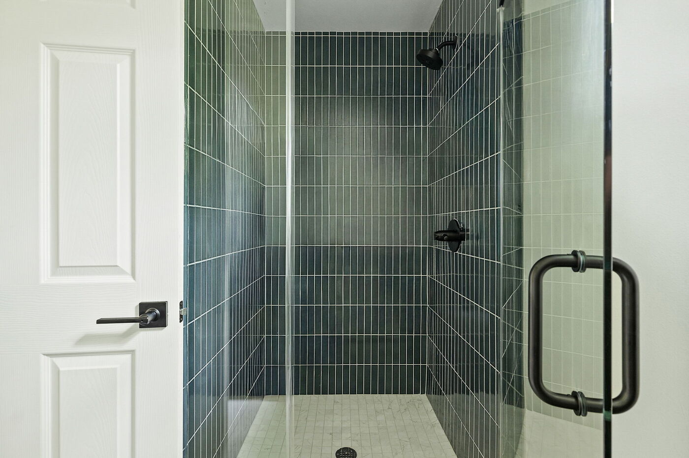 Walk-in shower with green tile and glass door in Brentwood, TX ADU by RedOven Builds
