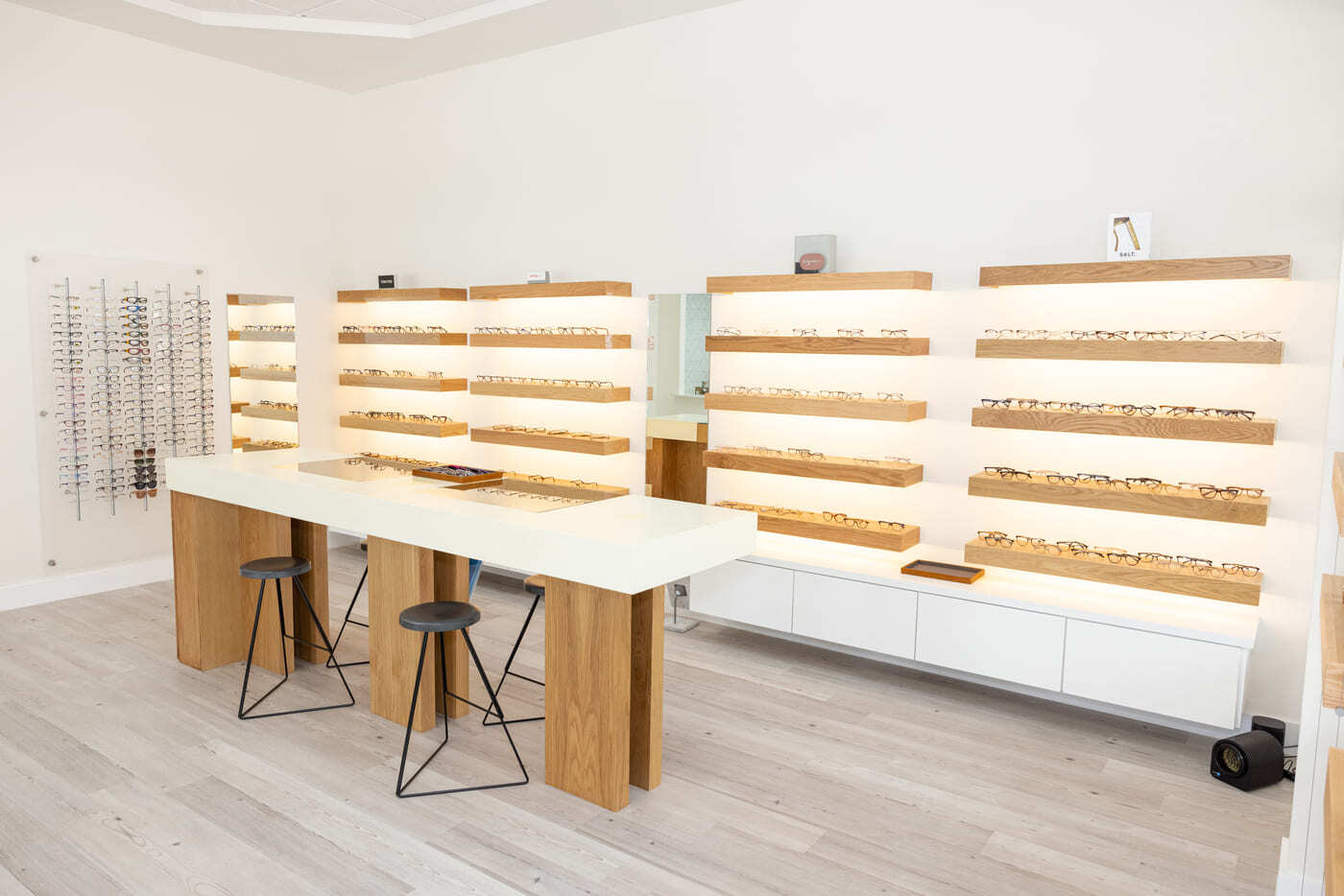 Eyewear display wall with illuminated shelving and seating in Austin, TX eye center by RedOven Builds
