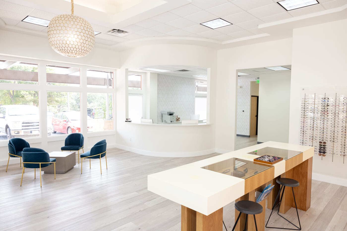 Modern eye center interior with seating area, display tables, and large windows in Austin, TX by RedOven Builds