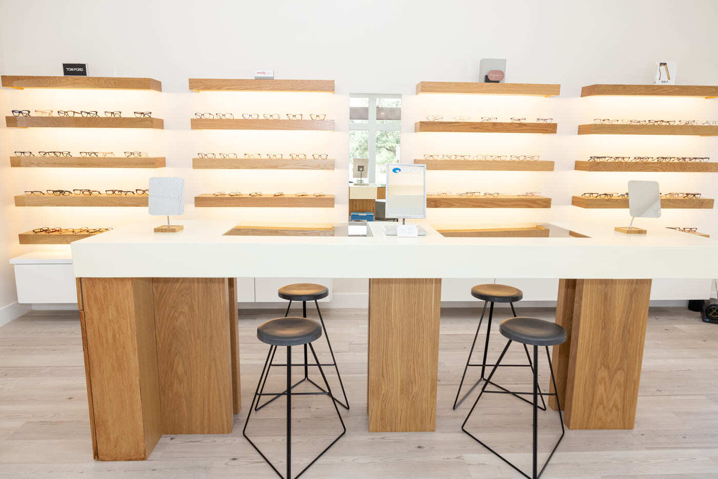 Optical display area with wood shelving and central table in Austin, TX eye center by RedOven Builds