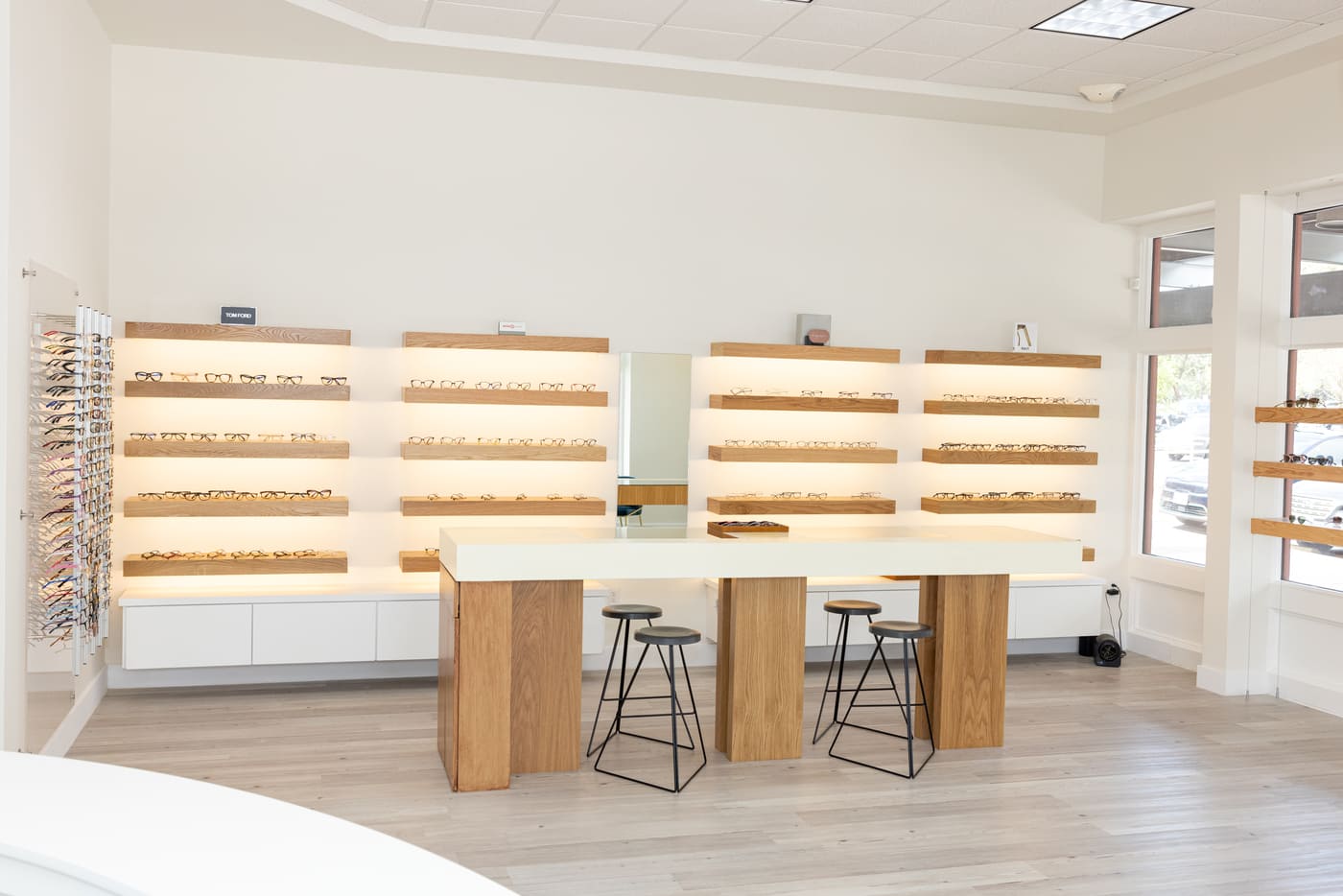 Optical retail area with wood display shelves and central table in Austin, TX eye center by RedOven Builds