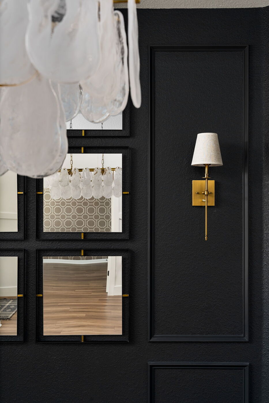 Black paneled wall with mirrors and brass sconce detail in Austin, TX remodel by RedOven Builds