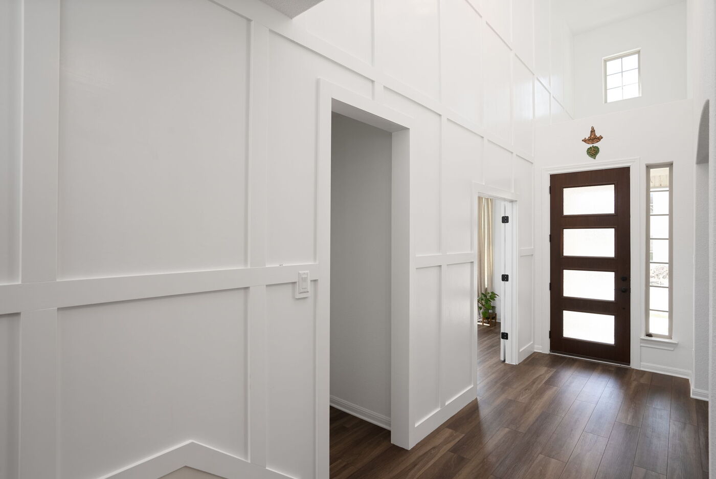 Bright entryway with white paneled walls and modern front door in Austin, TX remodel by RedOven Builds