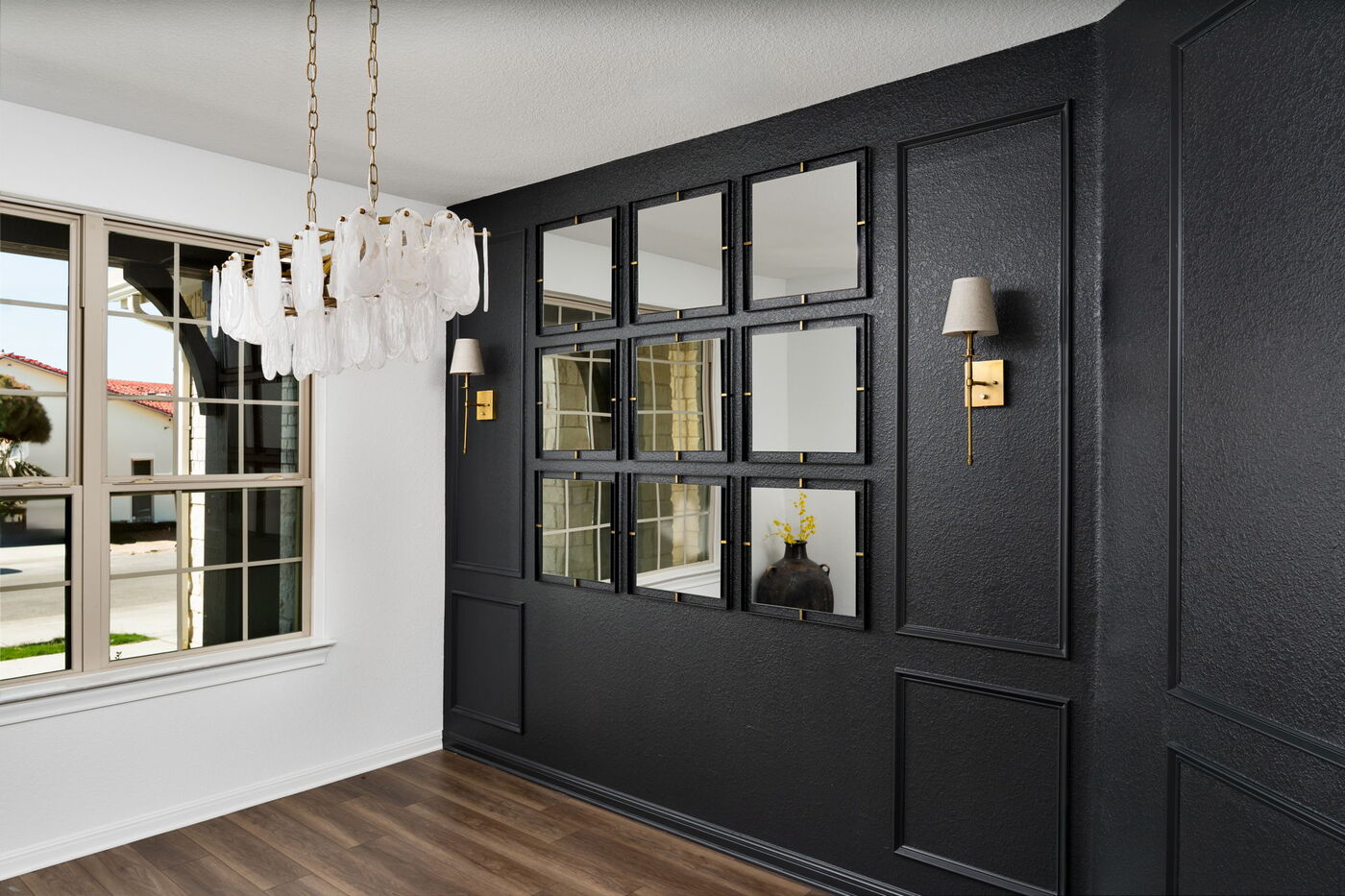 Dining space with black paneled wall, mirrors, and chandelier in Austin, TX remodel by RedOven Builds