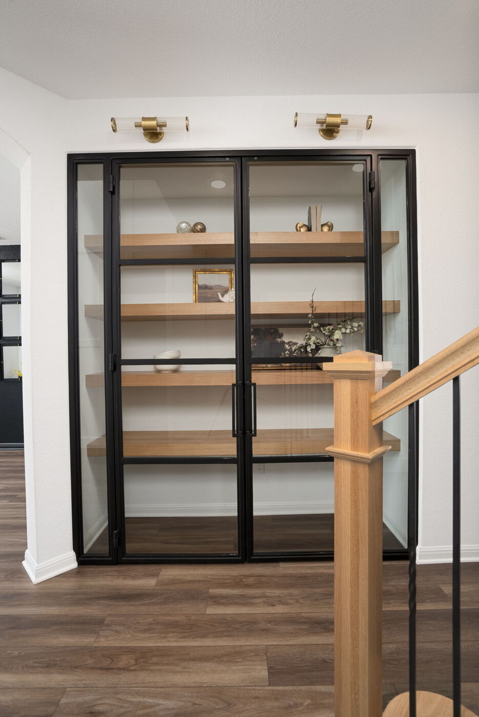 Glass-front built-in shelving with wood shelves near staircase in Austin, TX remodel by RedOven Builds