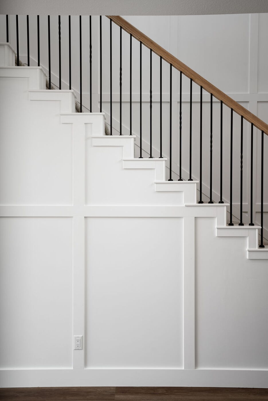 Staircase with white paneling and wood handrail detail in Austin, TX remodel by RedOven Builds