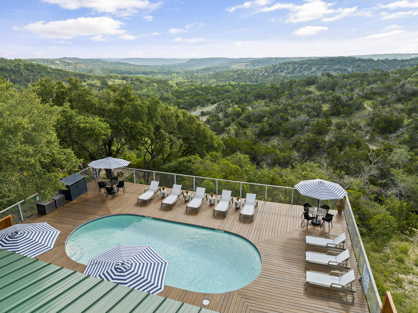 Aerial view of pool deck hotel renovation in Austin, TX by RedOven Builds with loungers and striped umbrellasa