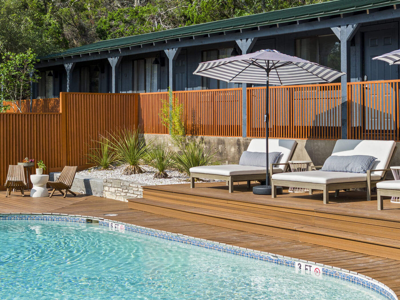 Close view of poolside lounge seating at hotel renovation in Austin, TX by RedOven Builds with wood deck and fencing