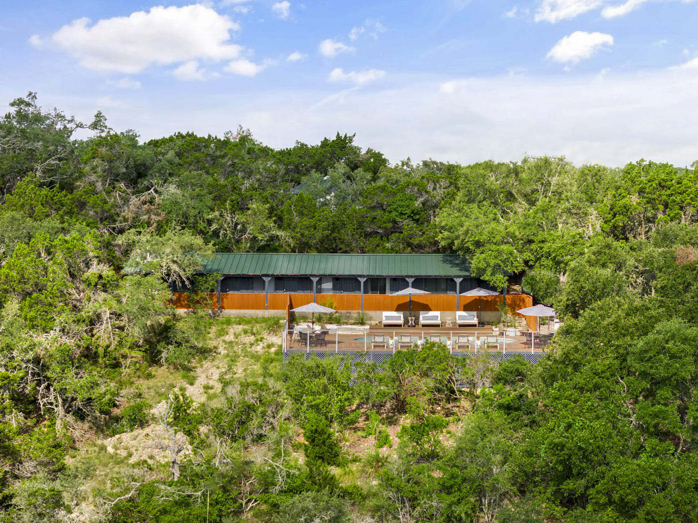 Hilltop hotel renovation in Austin, TX by RedOven Builds with modern pool deck and lush surrounding trees