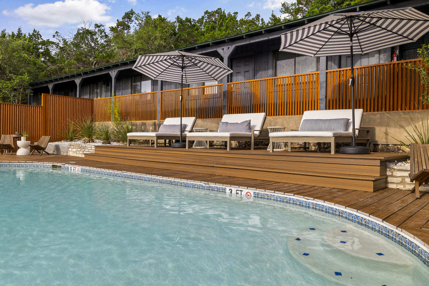 Hotel renovation pool deck in Austin, TX by RedOven Builds with lounge chairs, striped umbrellas, and wood decking