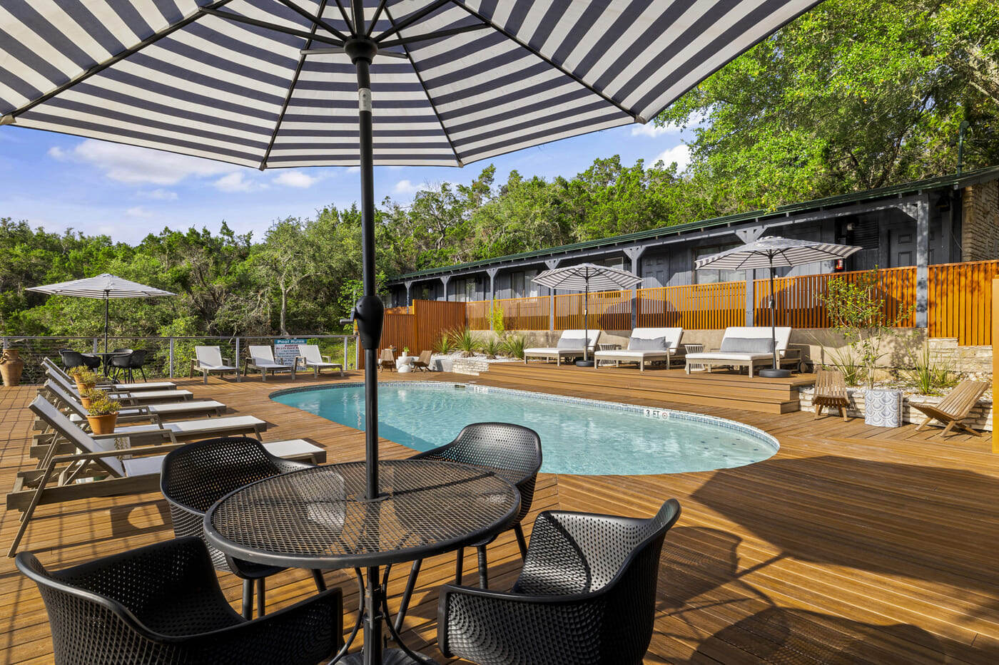 Outdoor seating and pool area at a hotel renovation in Austin, TX by RedOven Builds with striped umbrellas and wood decking