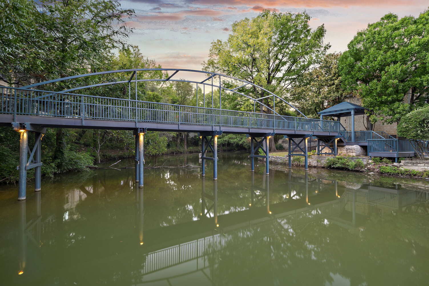 RedOven Builds commercial remodel bridge over water at sunset at 4408 Long Champ Dr Austin TX with illuminated supports