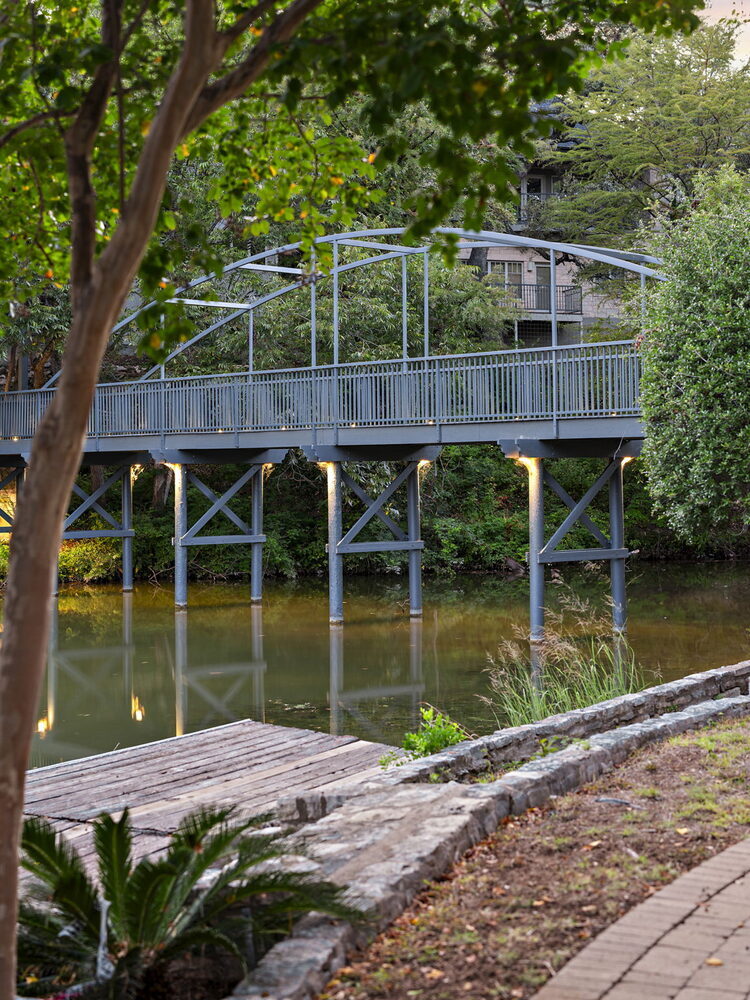 RedOven Builds commercial remodel landscaped walkway and bridge view at 4408 Long Champ Dr Austin TX framed by trees