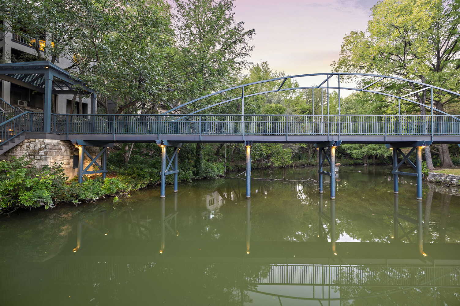 RedOven Builds commercial remodel wide pedestrian bridge over water at 4408 Long Champ Dr Austin TX with natural landscape