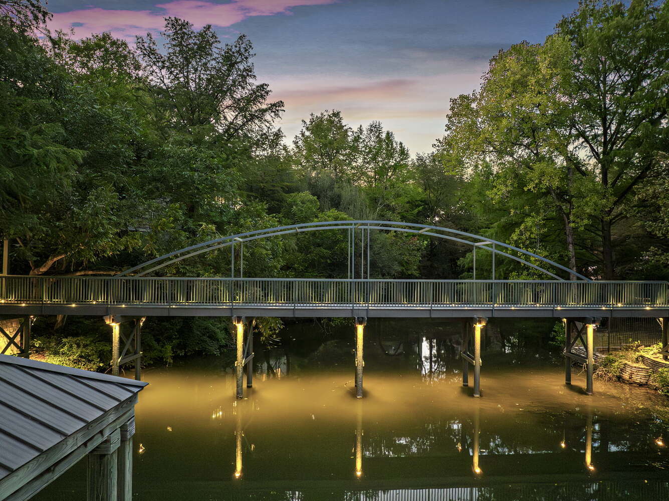 custom bridge with lighting reflecting on water from RedOven Builds commercial remodel Austin TX