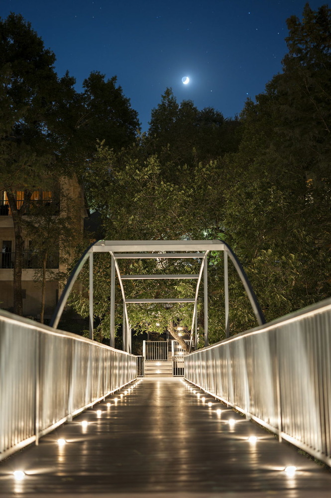 illuminated pedestrian bridge path under night sky by RedOven Builds in Austin TX