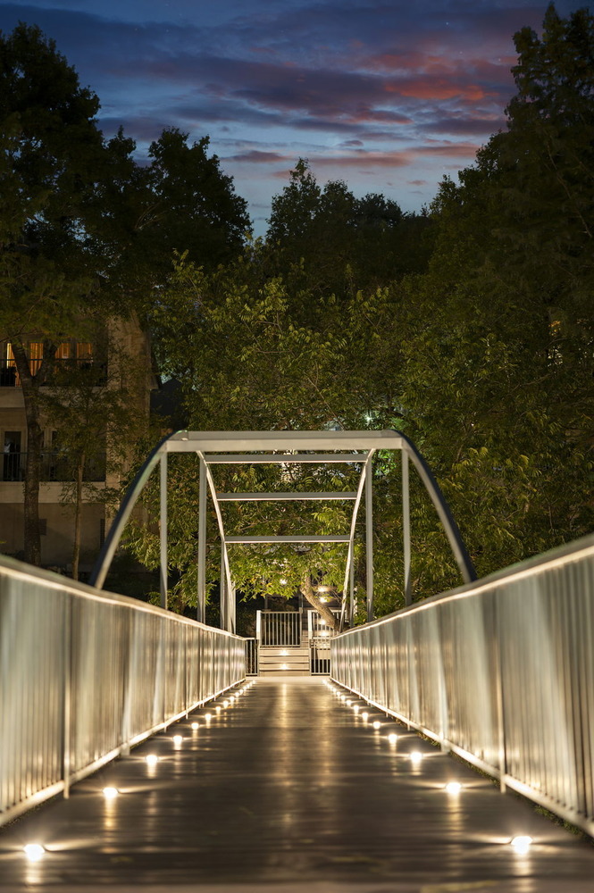 night scene of modern bridge with deck lights from RedOven Builds commercial remodel Austin TX