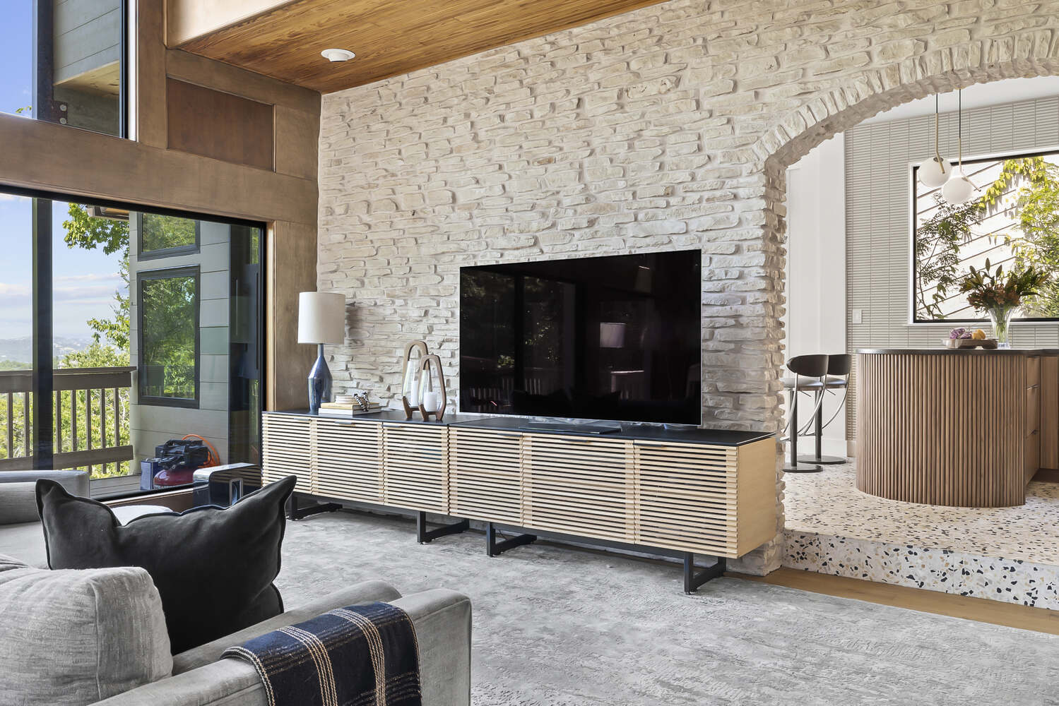 Austin TX remodel by RedOven Builds featuring cozy living room with stone wall and adjacent modern kitchen