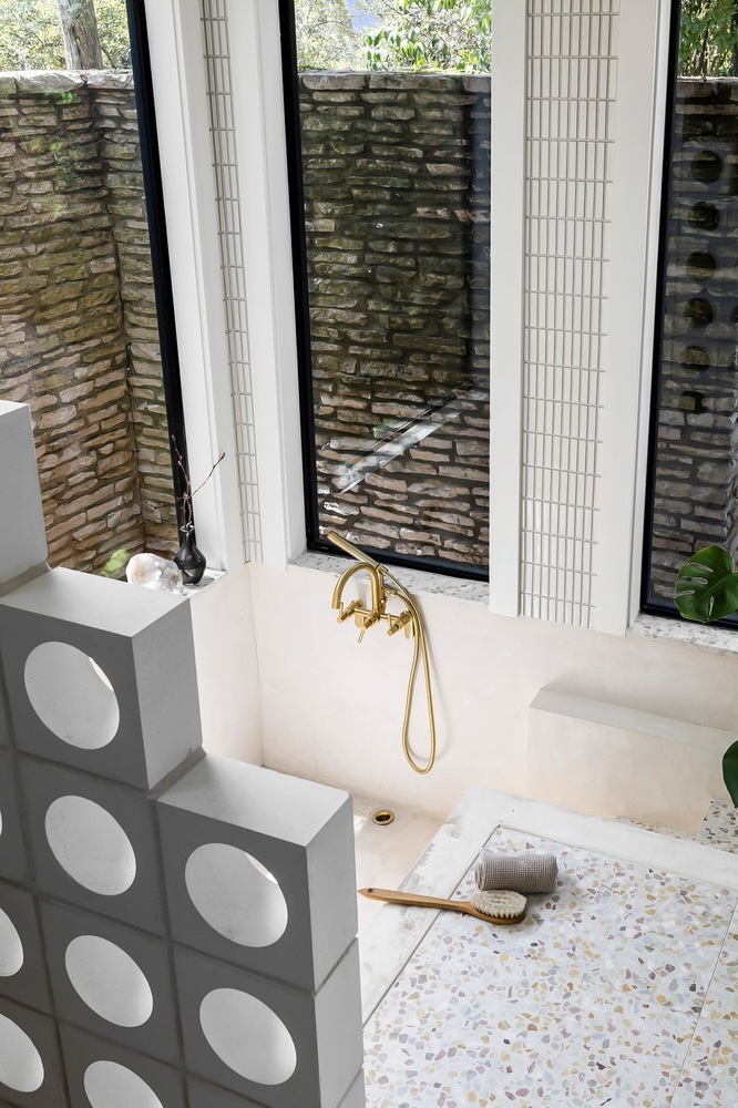 Bathroom soaking tub with gold fixture and large windows in a RedOven Builds remodel in Austin, TX
