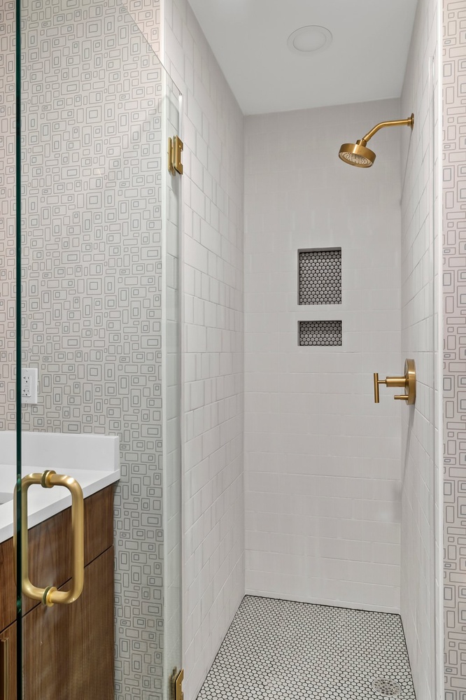 Minimalist shower design with built-in niches and gold hardware in Austin TX by RedOven Builds