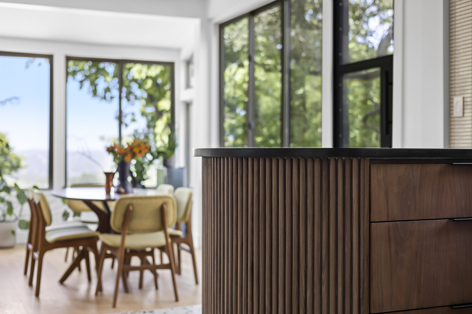 RedOven Builds full home remodel in Austin TX featuring a modern kitchen island with wood slat detailing and open dining area with large windows