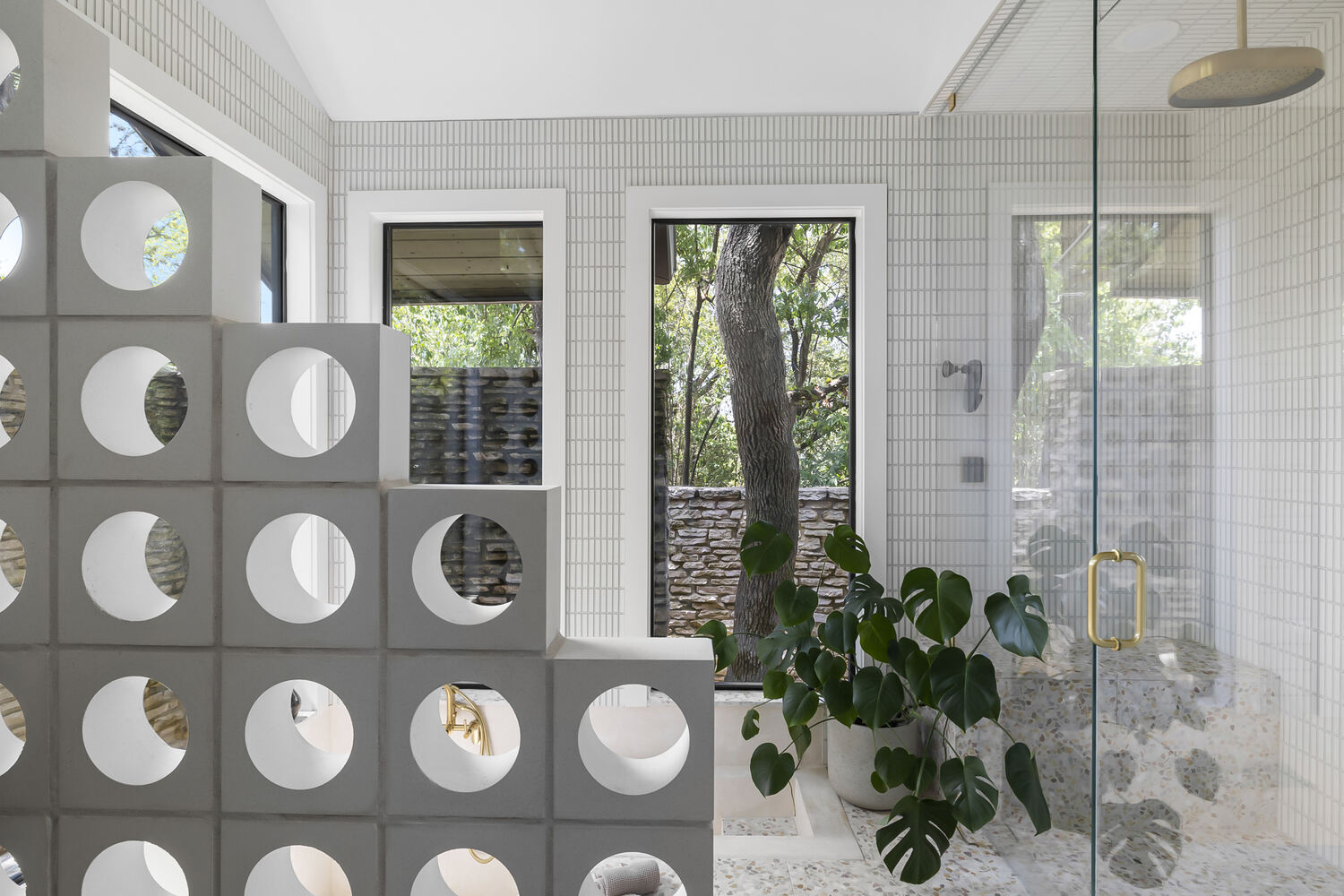 Walk-in shower with glass enclosure and terrazzo floor in a RedOven Builds Austin TX remodel