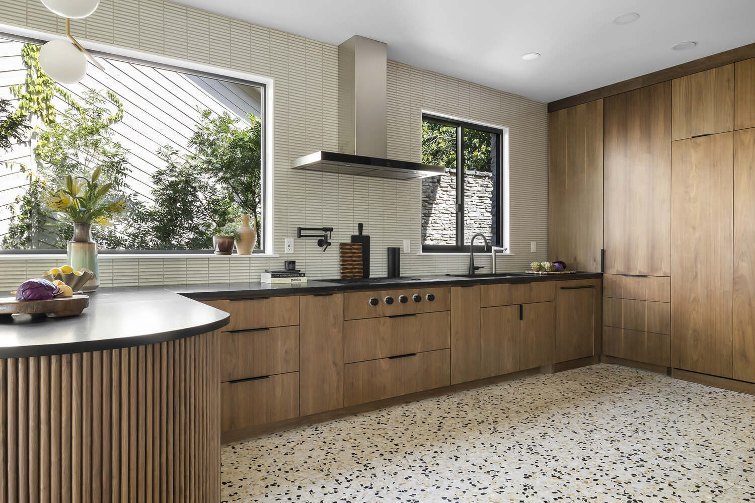 bright kitchen with large windows walnut cabinets and terrazzo floors by RedOven Builds Austin TX remodel