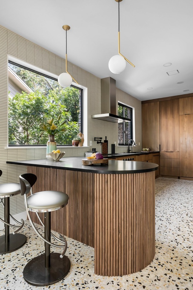 kitchen island with seating and modern lighting in remodeled home by RedOven Builds Austin TX