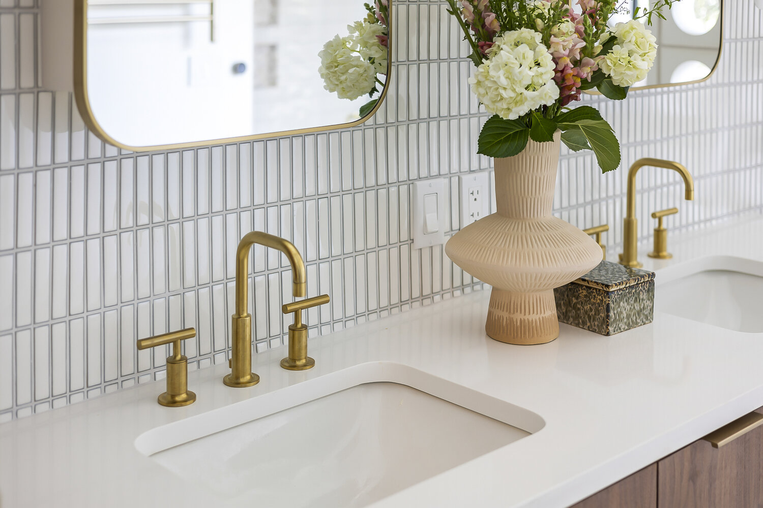 modern bathroom double vanity with brass fixtures and white tile backsplash in full home remodel by RedOven Builds in Austin TX