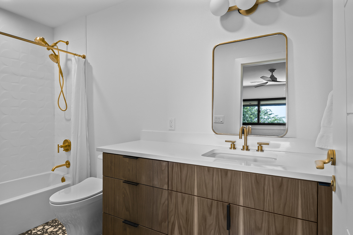 modern bathroom remodel with walnut vanity and gold fixtures by RedOven Builds in Austin TX