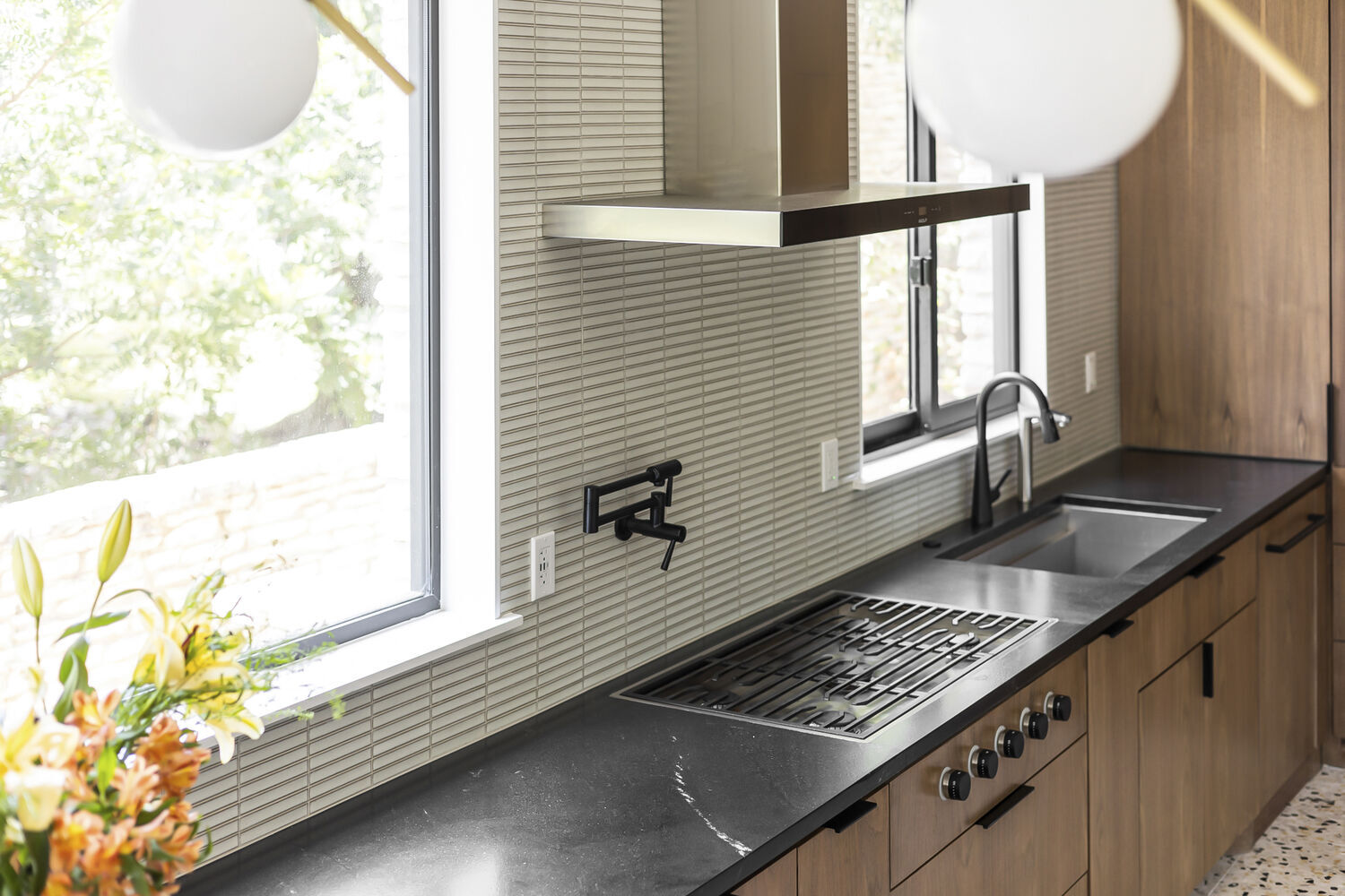 modern kitchen cooktop with black countertop and wood cabinetry in Austin TX remodel by RedOven Builds