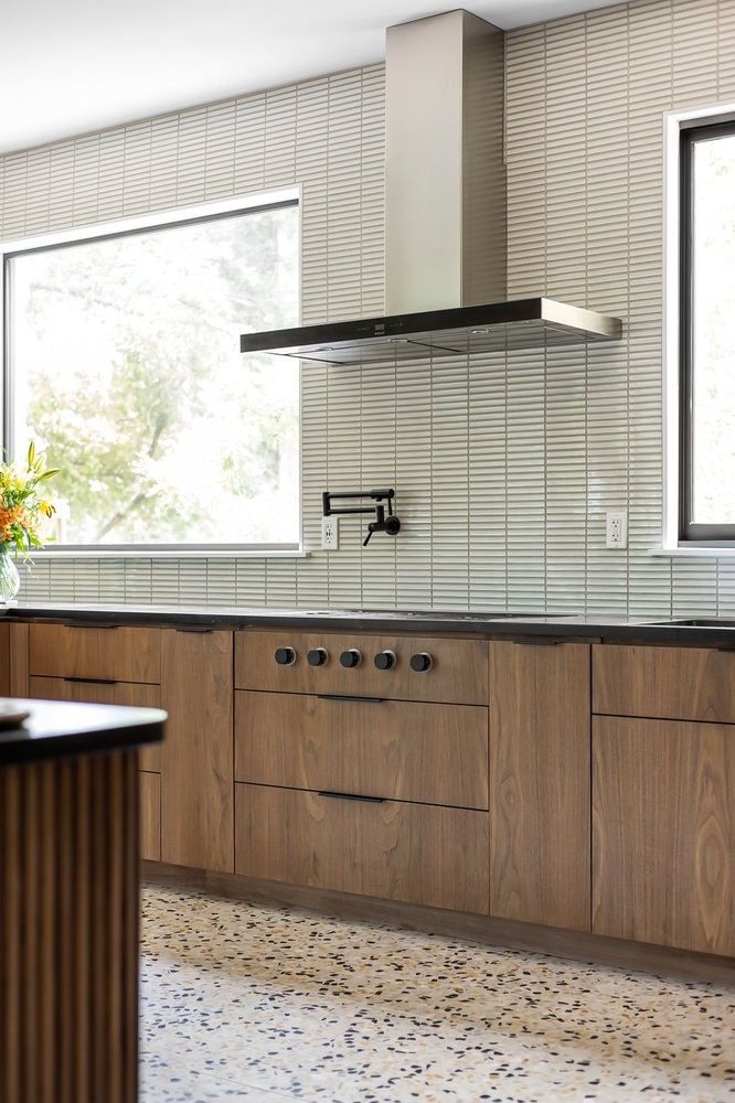 modern kitchen with wood cabinets and large windows by RedOven Builds Austin TX remodel