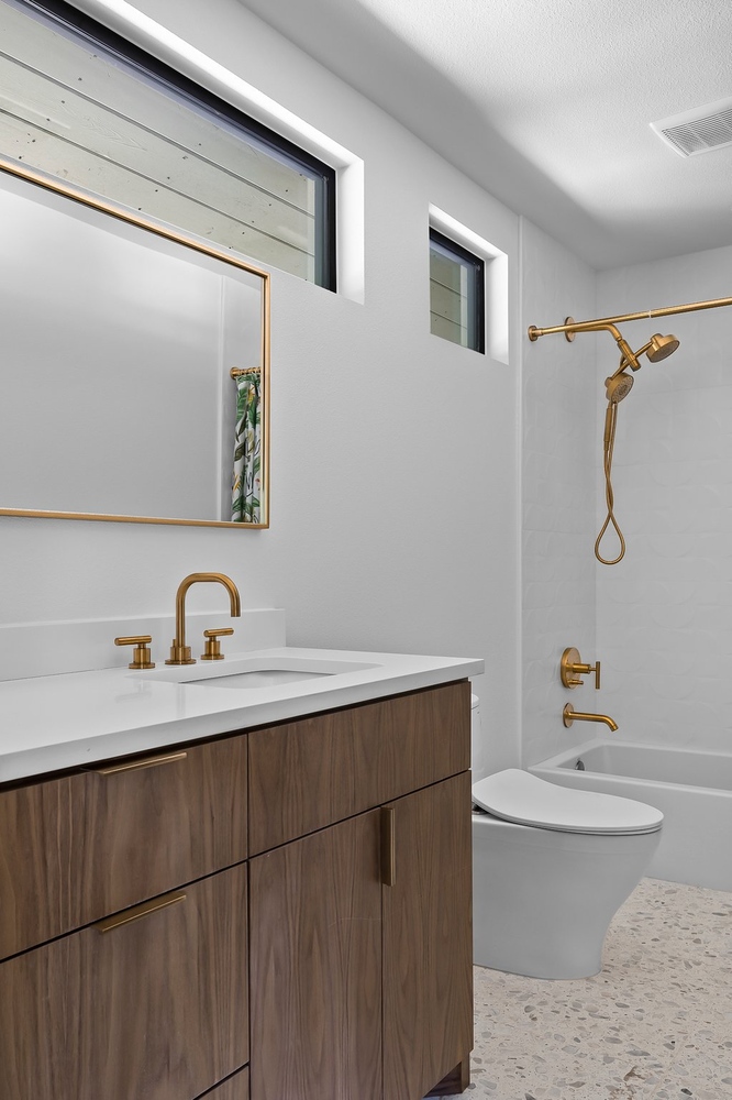 sleek bathroom design with wood vanity and white tile in Austin TX by RedOven Builds